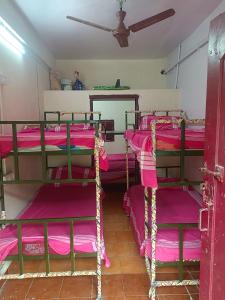 a room with three bunk beds with pink sheets at J Rooms&Dormentary in Madurai