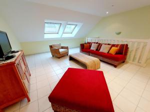 a living room with a red couch and a tv at Gîte Saint-Mars-sur-la-Futaie, 4 pièces, 6 personnes - FR-1-600-94 in Saint-Mars-sur-la-Futaie