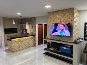 een woonkamer met een tv aan een bakstenen muur bij Pousada Ferreira 415 in São Gabriel