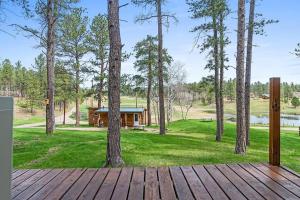 a wooden deck with a cabin in the woods at Little Joy BHBungalows #4 in Custer