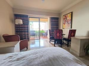 a bedroom with a bed and chairs and a balcony at Paraíso Escondido in Cabo San Lucas