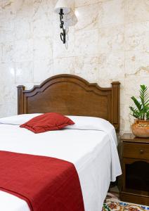 a bedroom with a bed with a red and white blanket at La Aurora Hotel Colonial in Valladolid