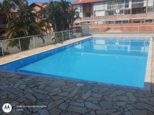 uma grande piscina com água azul em Flat Maranduba Ville em Ubatuba