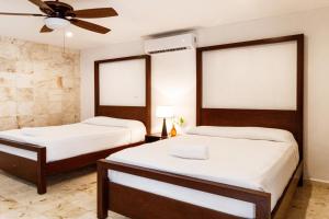een slaapkamer met 2 bedden en een plafondventilator bij La Aurora Hotel Colonial in Valladolid