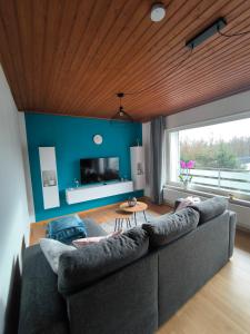 - un salon avec un canapé gris et un mur bleu dans l'établissement Haus am ruhige Lage in Langscheid Nähe sorpesee, à Melschede