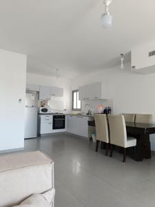 uma cozinha branca com mesa e cadeiras em Lovely room at Benny's apartment em Netivot