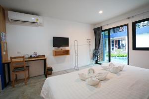 a bedroom with a white bed with white towels on it at KRAAM Silhouette Hotel & Cafe Phuket in Ban Kata