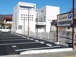 Iidamachiにあるビジネスホテル 山手INNの建物前の看板付き駐車場