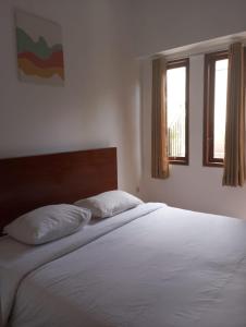 ein Schlafzimmer mit einem Bett mit zwei Kissen und zwei Fenstern in der Unterkunft Amelle Villas & Residences Canggu in Canggu
