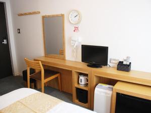a room with a desk with a television and a mirror at ビジネスホテル 山手INN in Iidamachi