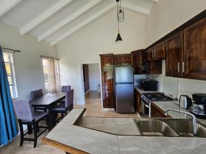 a kitchen with wooden cabinets and a table and a kitchen with a dining room at Royal Escape - 2 in Anse La Raye