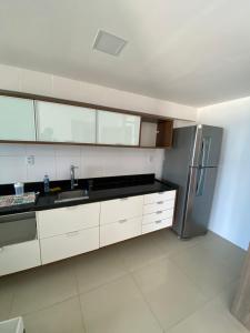 cocina con armarios blancos y nevera de acero inoxidable en Apartamento beira mar Salvador Bahia, en Salvador