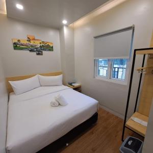 TRAVELBIZ HOTEL في ميدان: غرفة نوم بسرير ابيض ونافذة