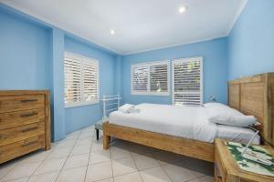 a blue bedroom with a large bed and windows at Heart of Peregian in Peregian Beach