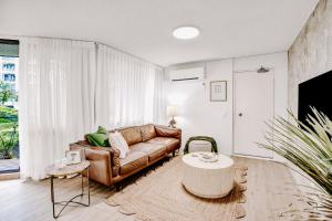 a living room with a leather couch and a table at Beachfront Beauty in Alexandra Headland