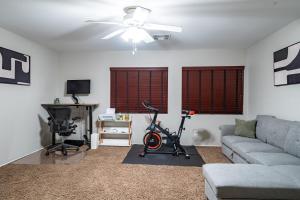 a living room with a couch and a bike and a desk at 5BR 3BA Family friendly entire home w pool, spa, games, tvs, and more in Las Vegas