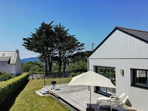una casa bianca con terrazza in legno con ombrellone di Maison Crozon, 4 pièces, 6 personnes - FR-1-370-37 a Crozon