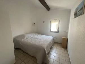 1 dormitorio con cama blanca y ventana en Appartement Saintes-Maries-de-la-Mer, 3 pièces, 6 personnes - FR-1-475-29, en Saintes-Maries-de-la-Mer