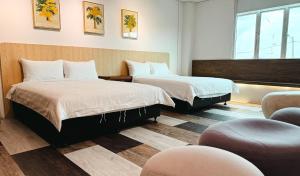 a hotel room with two beds and a chair at Inang Street Stay - Cheng Business Park in Melaka
