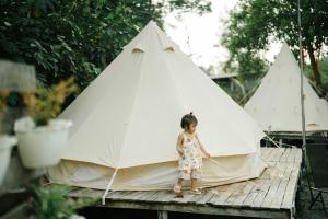 a little girl standing in front of a teepee at An Suối Garden Tri Tôn An Giang 