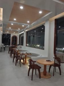 TRAVELBIZ HOTEL في ميدان: غرفة طعام مع طاولات وكراسي وحوض استحمام