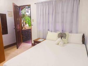 Un dormitorio con una gran cama blanca y una ventana. en Jurias Garden Hotel, en El Nido 67 fotos más