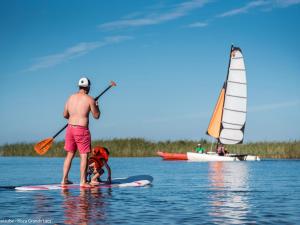 un homme et un enfant sur une planche de paddle dans l'eau dans l'établissement Maison Sanguinet, 3 pièces, 4 personnes - FR-1-319-408, à Sanguinet