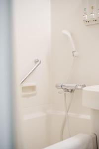 a white bathroom with a shower and a sink at Hakata Nakasu Washington Hotel Plaza in Fukuoka