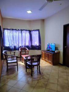 a living room with chairs and a table and a tv at Homestay Elina - Cheap and cosy in Port Dickson