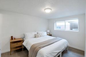 a white bedroom with a bed and a window at Just Minutes from UVU Fully Fenced Backyard in Orem