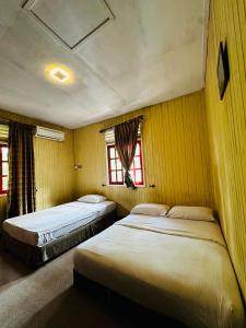 two beds in a room with two windows at KEMBARA RESORT in Setiu