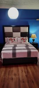 a bedroom with a large bed with a blue wall at Master Palace Guest House - Randfontien in Randfontein