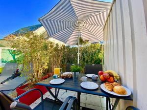 stół z talerzami jedzenia i parasolką w obiekcie Appartement calme à 3 min de la plage avec terrasse, parking et WIFI - FR-1-714-1 w mieście Clohars-Carnoët