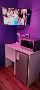 a pink table with a microwave and a tv at Master Palace Guest House - Randfontien in Randfontein