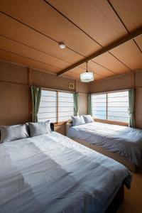 two beds in a room with two windows at HATSUNE in Otaru
