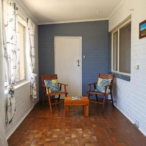 een veranda met 2 stoelen, een tafel en een deur bij The Winemakers Quarters in Tanunda
