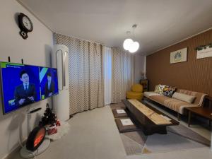 ein Wohnzimmer mit einem Sofa und einem TV an der Wand in der Unterkunft Soo Stay-4bed&Double Room, Hongdae, Sinchon 10min in Seoul