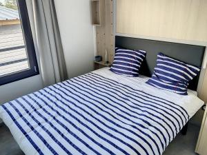 een bed met blauwe en witte gestreepte lakens en een raam bij Chalet Jullouville, 4 pièces, 6 personnes - FR-1-361-518 in Jullouville-les-Pins