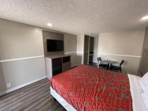 a hotel room with a bed and a flat screen tv at Economy Inn in San Bernardino