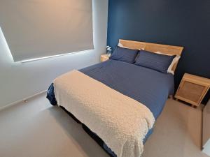 a bedroom with a large bed with blue walls at Omanu Cottage in Mount Maunganui