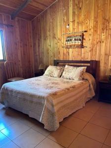 1 dormitorio con 1 cama con pared de madera en Cabaña Flor de Lican, en Licán Ray