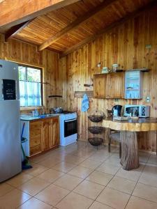 cocina con armarios de madera y nevera blanca en Cabaña Flor de Lican, en Licán Ray