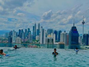een groep mensen die zwemmen in een overloopzwembad met een skyline van de stad bij Regalia service suites klcc skypool in Kuala Lumpur