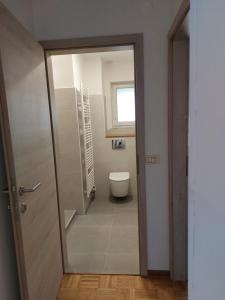een badkamer met een toilet en een raam en een deur bij Apartma BALC in Koper
