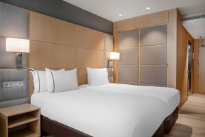 un grande letto bianco in una camera d'albergo di AC Hotel Victoria Suites by Marriott a Barcellona