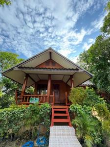 Cette petite maison est dotée d'un grand toit et d'un escalier. dans l'établissement Baan Ja Da, à Ban Nai Khlong