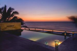 una piscina con vistas al océano al atardecer en Dco Suites Lounge & Spa, en Máncora