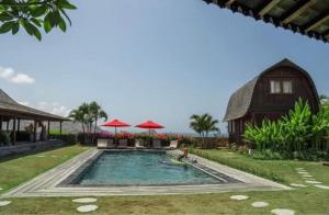 a swimming pool in front of a house at Villa Ellya in Kuta Lombok