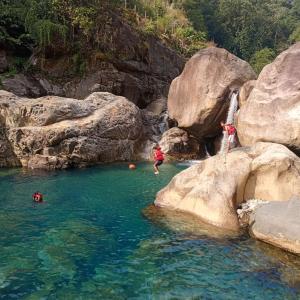 2 personnes nageant dans une rivière avec des rochers dans l'établissement Living Roots Lodge, à Cherrapunji