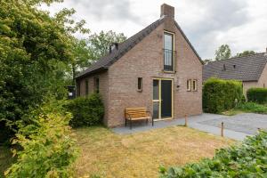 una casa de ladrillo con un banco delante de ella en Het Huys Ewijk mooi luxe en een laadpaal, en Ewijk